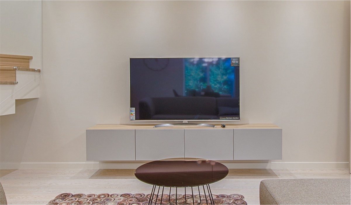 A Smart tV on a TV drawer with a coffee table in front of it in a modern living room